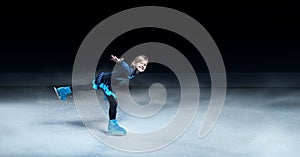 child  figure skater on dark ice arena background