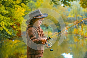 Child fishing at autumn lake. Kid with fishingrod.