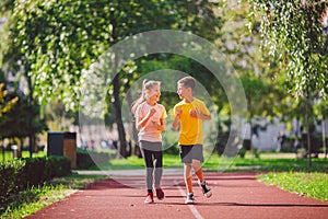 Child fitness, twins kids running on stadium track in city park , training and children sport healthy lifestyle. Outdoor