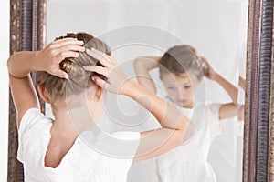 Child fixing her hair while looking in the mirror.