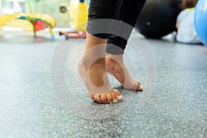 Child with flat feet standing on tiptoes during kinesiotherapy