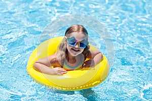 Child on float in swimming pool. Kids sunglasses.