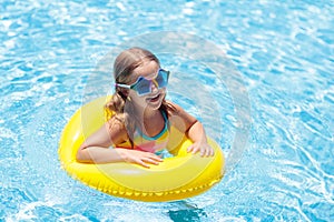 Child on float in swimming pool. Kids sunglasses