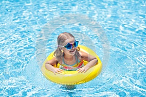Child on float in swimming pool. Kids sunglasses