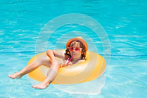 Child floating in pool. Child relaxing in pool, drink summer cocktail. Summer holidays and vacation with kids. Happy