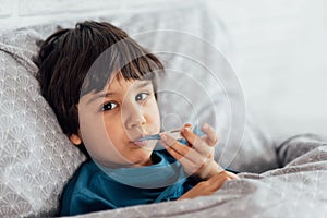 Child flu sick, boy with medical thermometer in mouth, health illness. Kid with cold rhinitis,