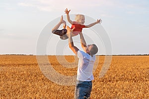 Child is flying in father arms. Dad tosses son into the air. Father and son playing outdoors