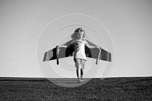 Child flying in plane made craft of cardboard wings. Dream, imagination, childhood. Travel and summer vacation concept