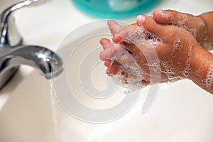 A child folding hands while washing with soap