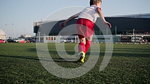 Child footballer is kicking a ball on stadium