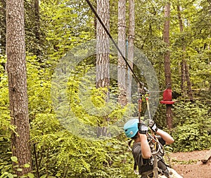 Child in forest adventure park. Kids climb on high rope trail. Agility and climbing outdoor amusement center for
