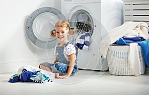 Child fun happy little girl to wash clothes in laundry room