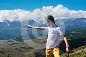 A child funny boy on the Altai mountain background.