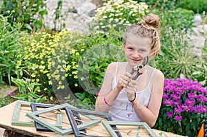 child with garden scissor and empty frames in the colorful garden