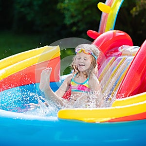 Child in garden swimming pool with slide