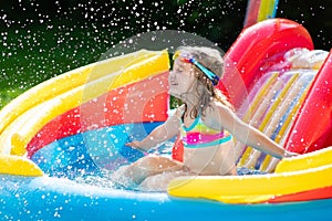 Child in garden swimming pool with slide