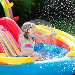 Child in garden swimming pool with slide