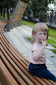 The child with the gesture SHH a walk in the summer park