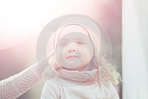 Child get hat put on head by female hands