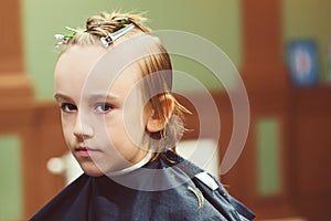 Child getting haircut by hairdresser at the barbershop. Barber shop