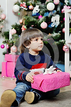 A child with a gift on a background of the Christmas tree