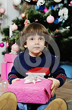 A child with a gift on a background of the Christmas tree