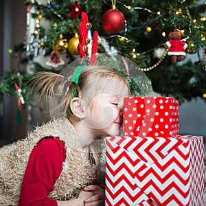 Child with a gift on the background of the Christmas tree. happy girl hugs