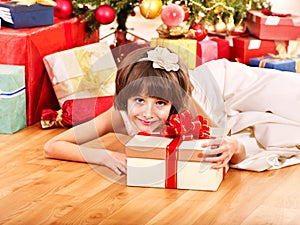 Child with gift box near Christmas tree.