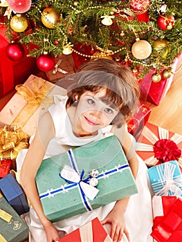 Child with gift box near Christmas tree.