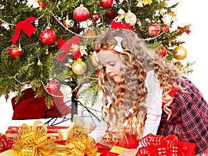 Child with gift box near Christmas tree.