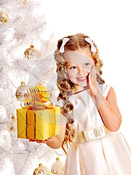 Child with gift box near white Christmas tree.