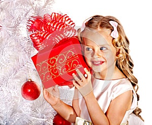 Child with gift box near white Christmas tree.