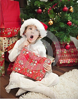 Child with gift in front of christmas tree