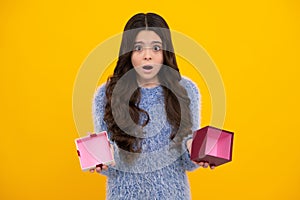 Child with gift present box on isolated studio background. Gifting for kids birthday. Unhappy sad teenager girl.