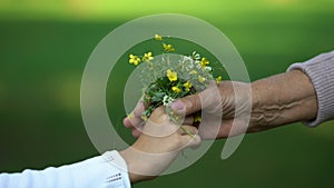 Child gifting bouquet of flowers to old grandmother, love and care, family