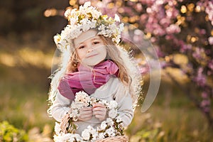 child girl 4-5 year old with flowers over blooming nature background close up. Spring season. Childhood