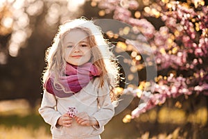 Child girl 4-5 year old with flowers over blooming nature background close up. Spring season. Childhood