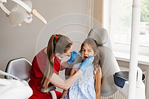 Child girl afraid dentist. Childrens dentist consults frightened kid in dentistry. Treatment of teeth and toothache in