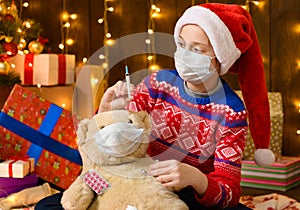 Child girl as Santa helper posing in new year decoration. Wearing a protective face mask against viruses, coronaviruses. She plays