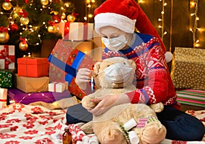 Child girl as Santa helper posing in new year decoration. Wearing a protective face mask against viruses, coronaviruses. She plays