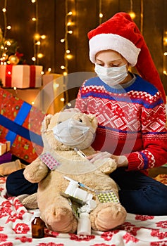 Child girl as Santa helper posing in new year decoration. Wearing a protective face mask against viruses, coronaviruses. She plays