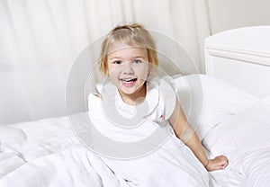 Child girl in bed smiling face..Toddler morning wake up.Caucasian little kid portrait