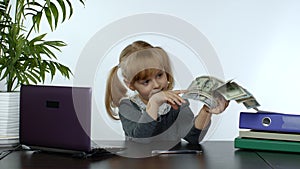 Child girl boss holding pile of dollar cash bills. Baby businesswoman kid holding money in hands