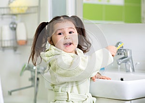 Child girl brushing teeth in bathroom