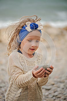 Child girl building stone tower on the beach