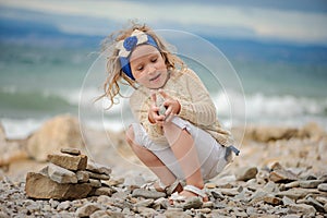 Child girl building stone tower on the beach