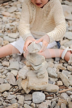 Child girl building stone tower on the beach