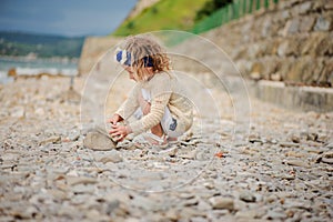 Child girl building stone tower on the beach in summer day