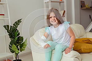 Child girl with a cast on a broken wrist or arm smiling at home