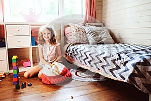 Child girl cleaning her room and organize wooden toys into knitted storage bag